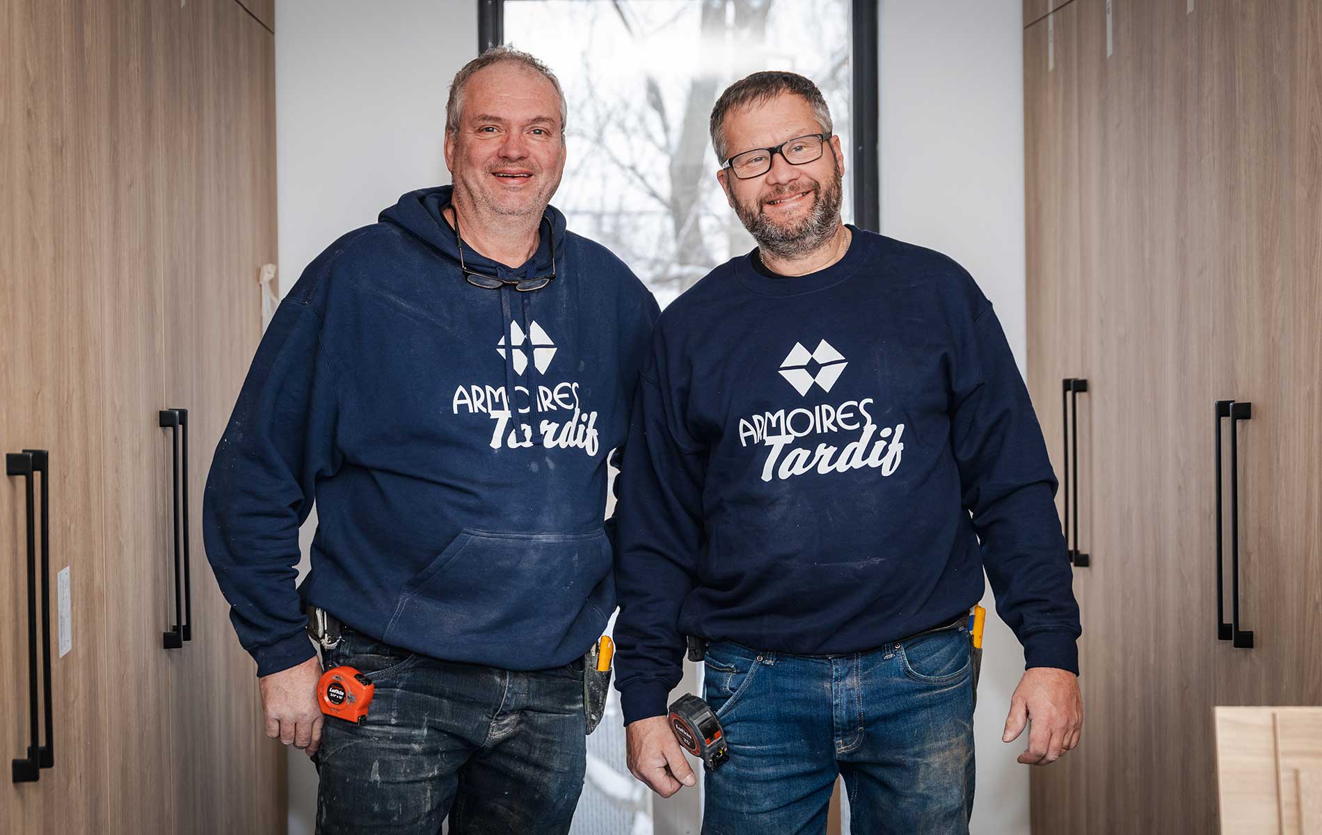 Deux menuisiers souriants en sweat-shirts bleus
