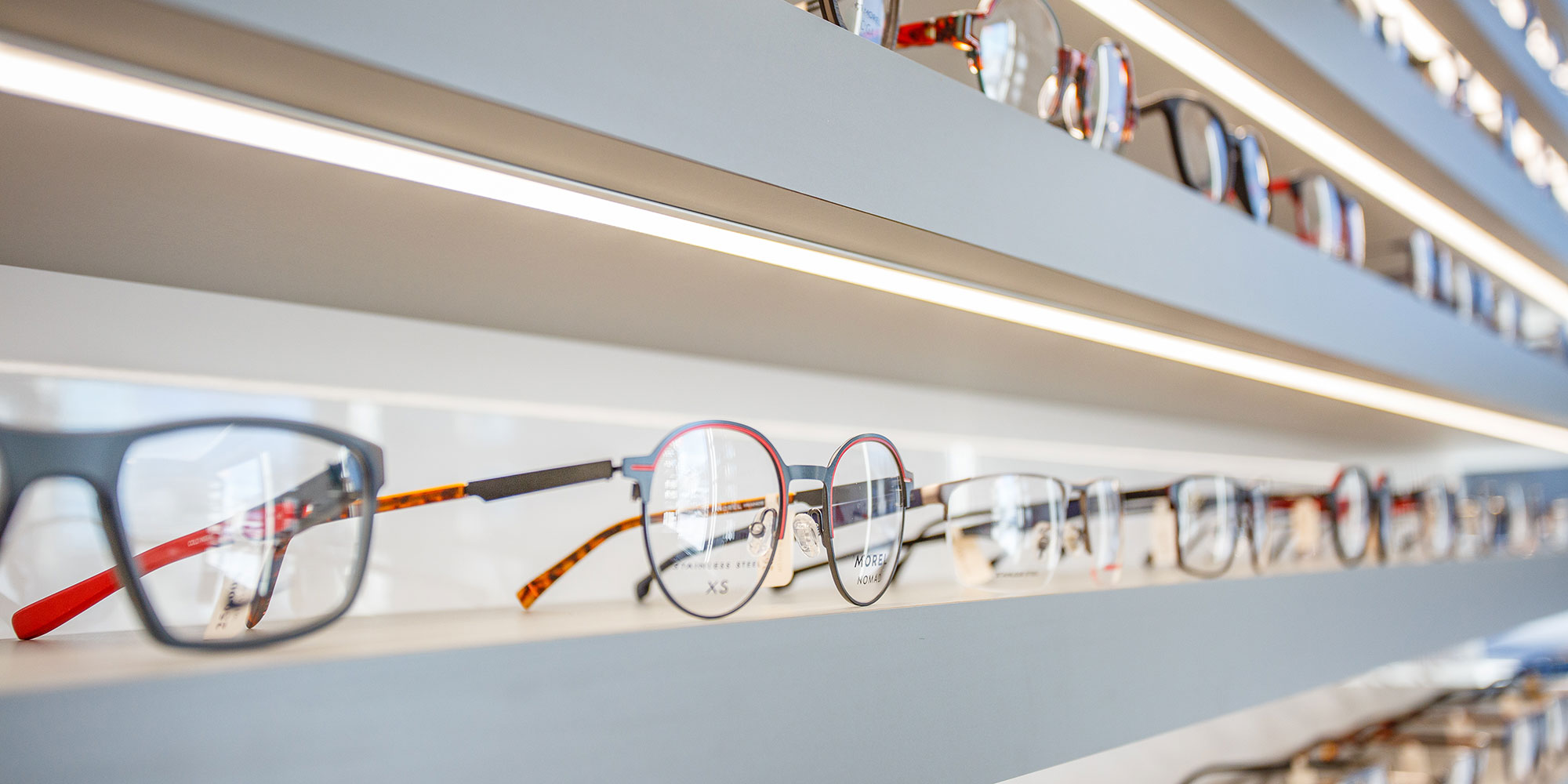 Lunettes variées sur étagères éclairées en magasin